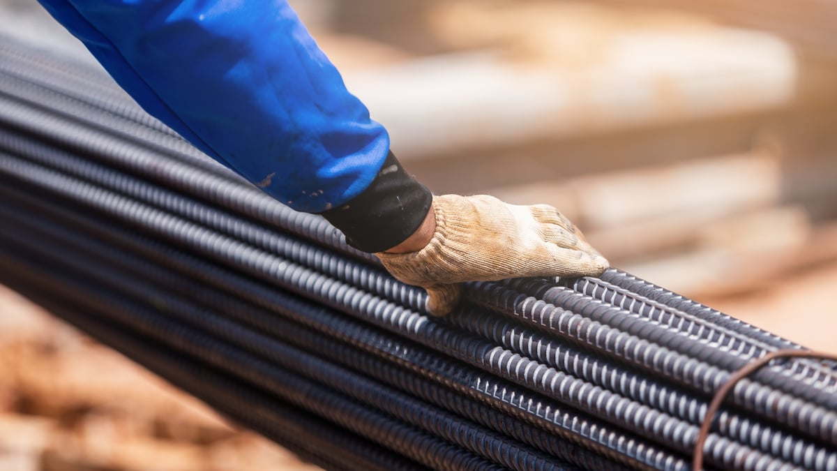 Gloved hand resting on a bundle of steel rebar at a construction site